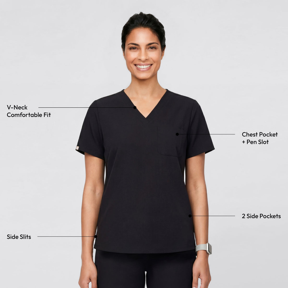 A person wearing an Eco Black V-neck scrub top with a three-pocket design, standing with a relaxed smile and one hand in the side pocket.