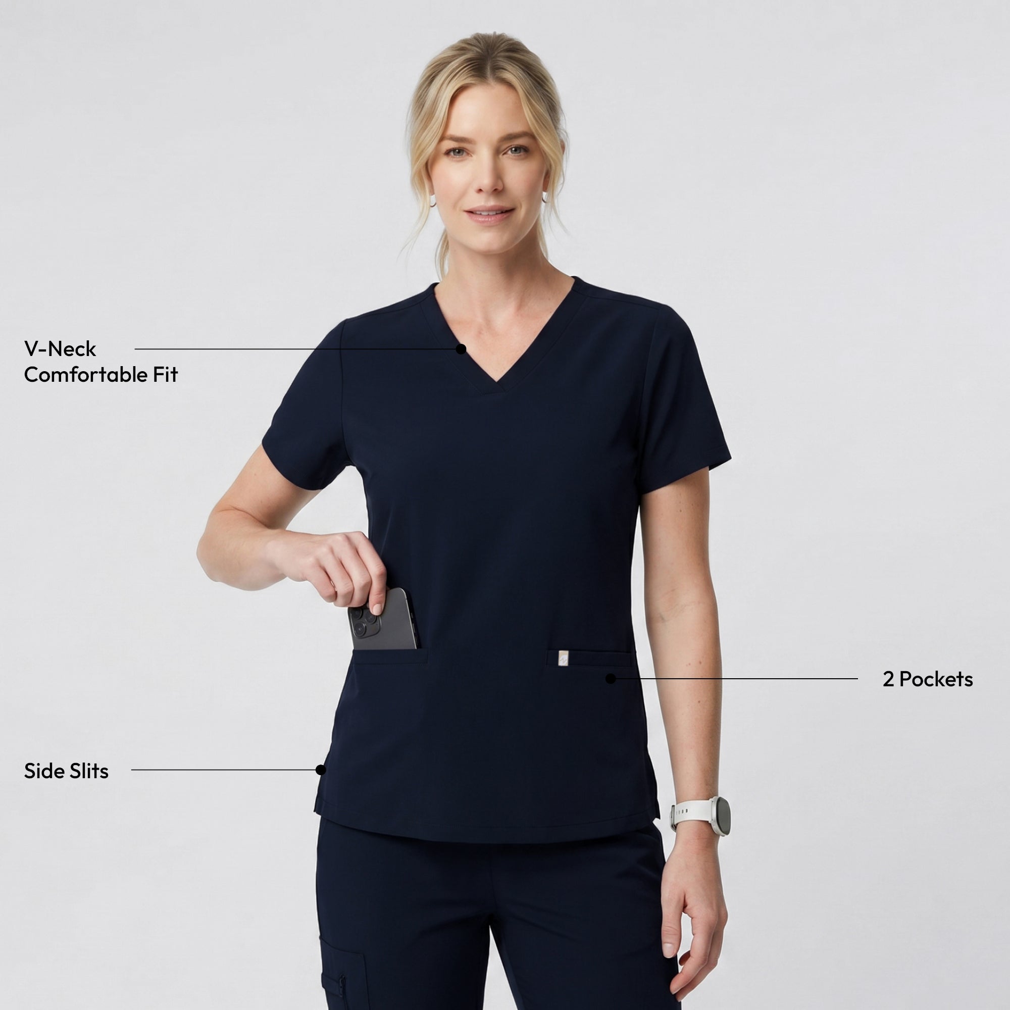 Model dressed in the Women's Eco Navy Double Pocket Scrub Top with pants, smiling with a yellow stethoscope and laptop in hand, upper body shot.