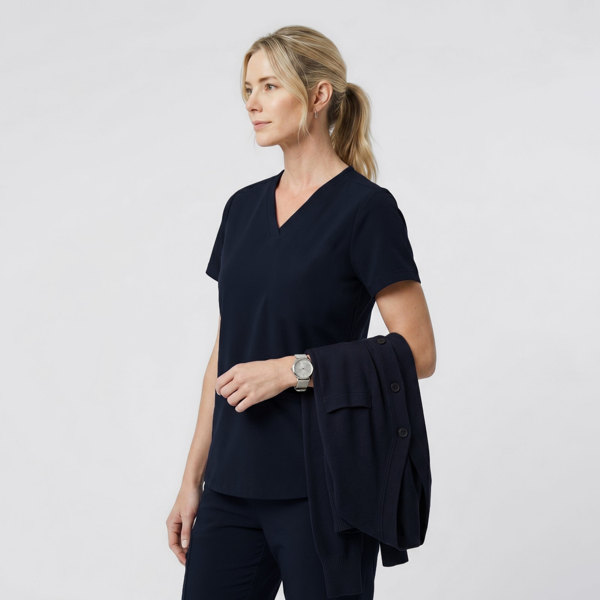 Side view of a model wearing the Eco Navy Double Pocket Scrub Top with hands in pockets.