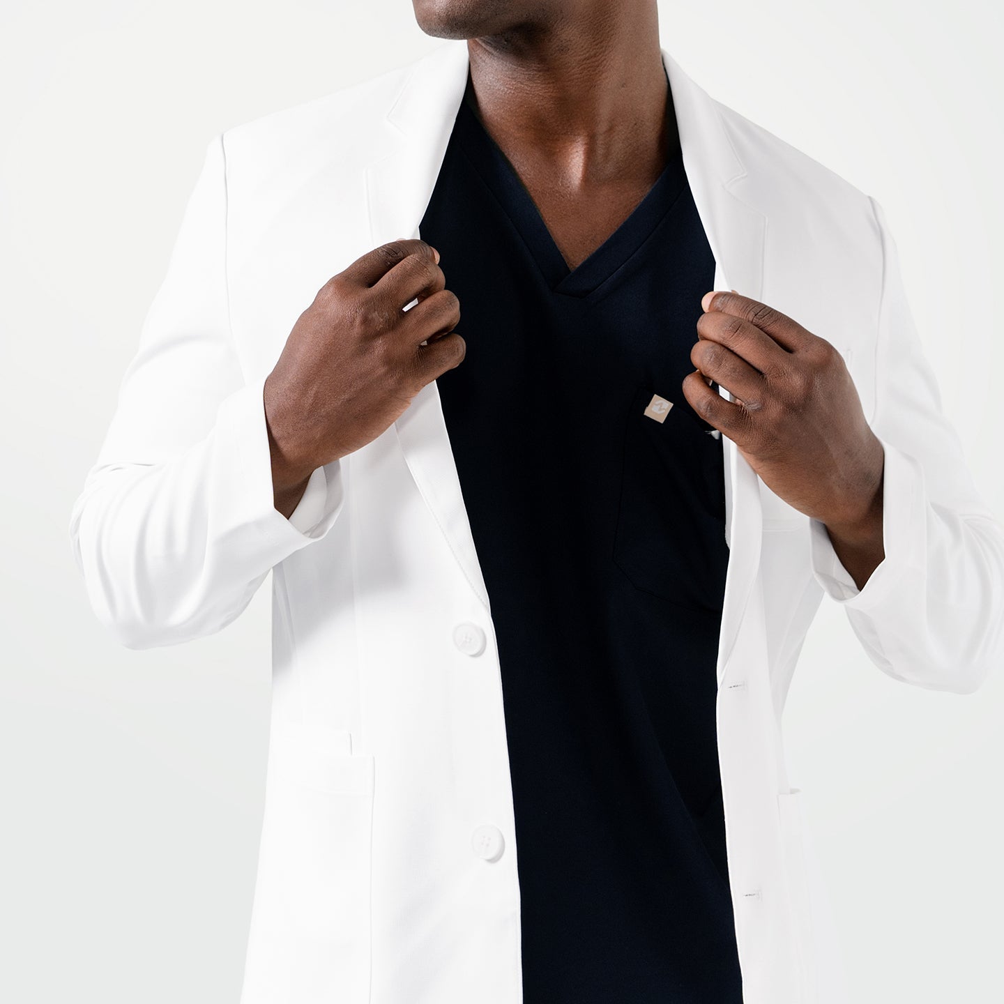 With both hands holding the lapels, the model showcases the sleek fit of the Men’s LCM-100 Lab Coat.
