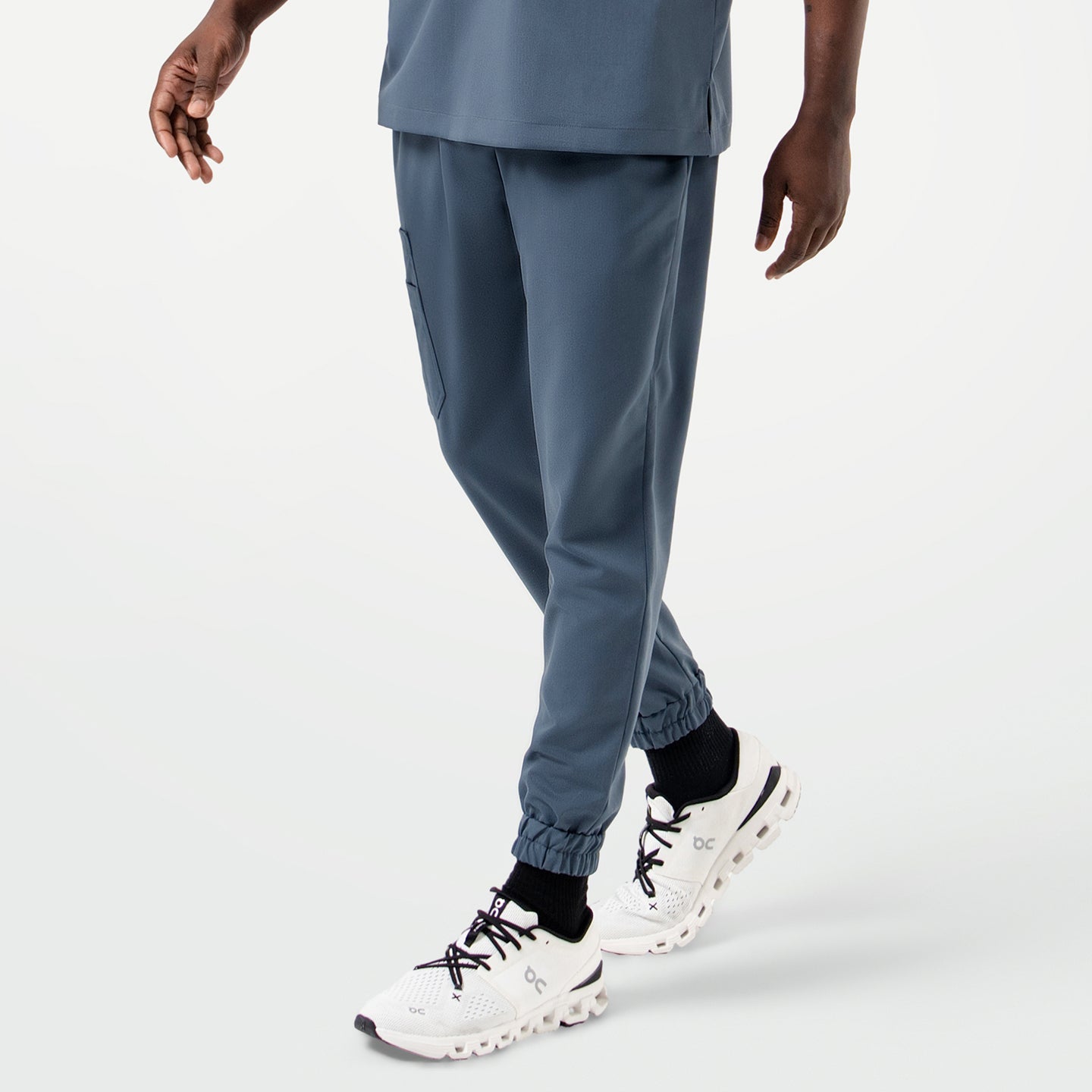 Close-up of the model wearing the StretchFit Jogger Scrub Pants in Smoky Blue while taking a step forward.