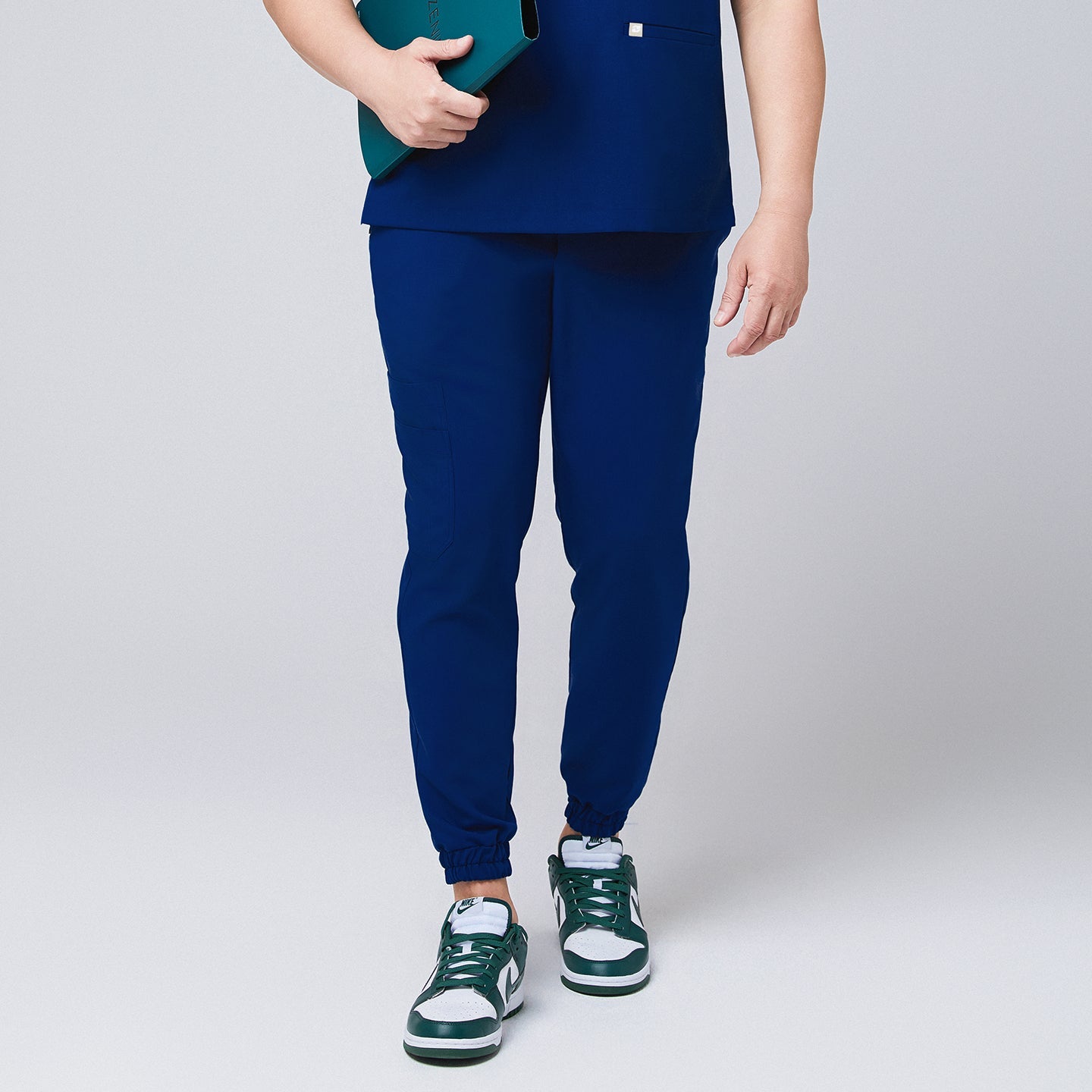Front view of Zenir Admiral Blue jogger scrub pants with elastic cuffs, paired with green sneakers, showcasing a professional and modern design, Admiral Blue