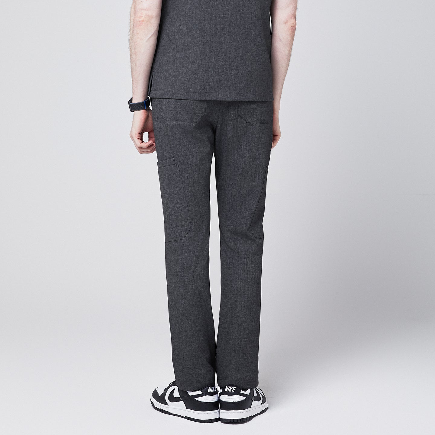 Back view of charcoal gray zipper straight scrub pants with side and back pockets, paired with black sneakers,Charcoal Gray