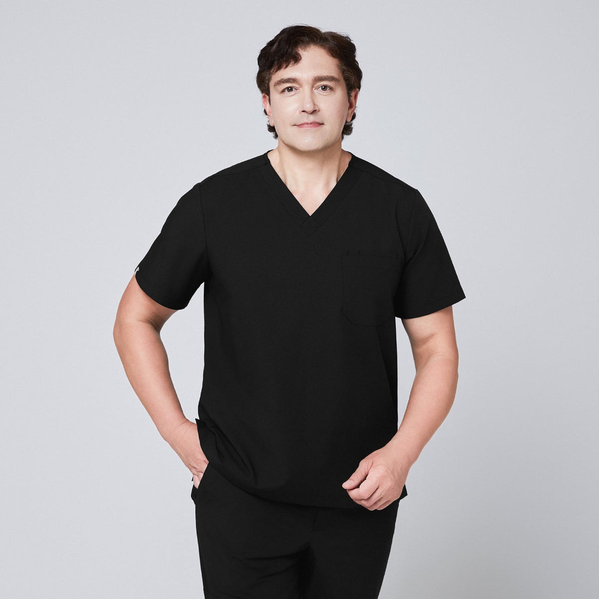 Model wearing an eco black 3-pocket scrub top with a V-neck design, styled with matching scrub pant,Eco Black