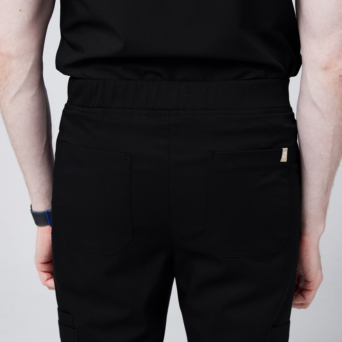 Close-up of the back view of black jogger scrub pants, showing back pockets and elastic waistband detail,Eco Black