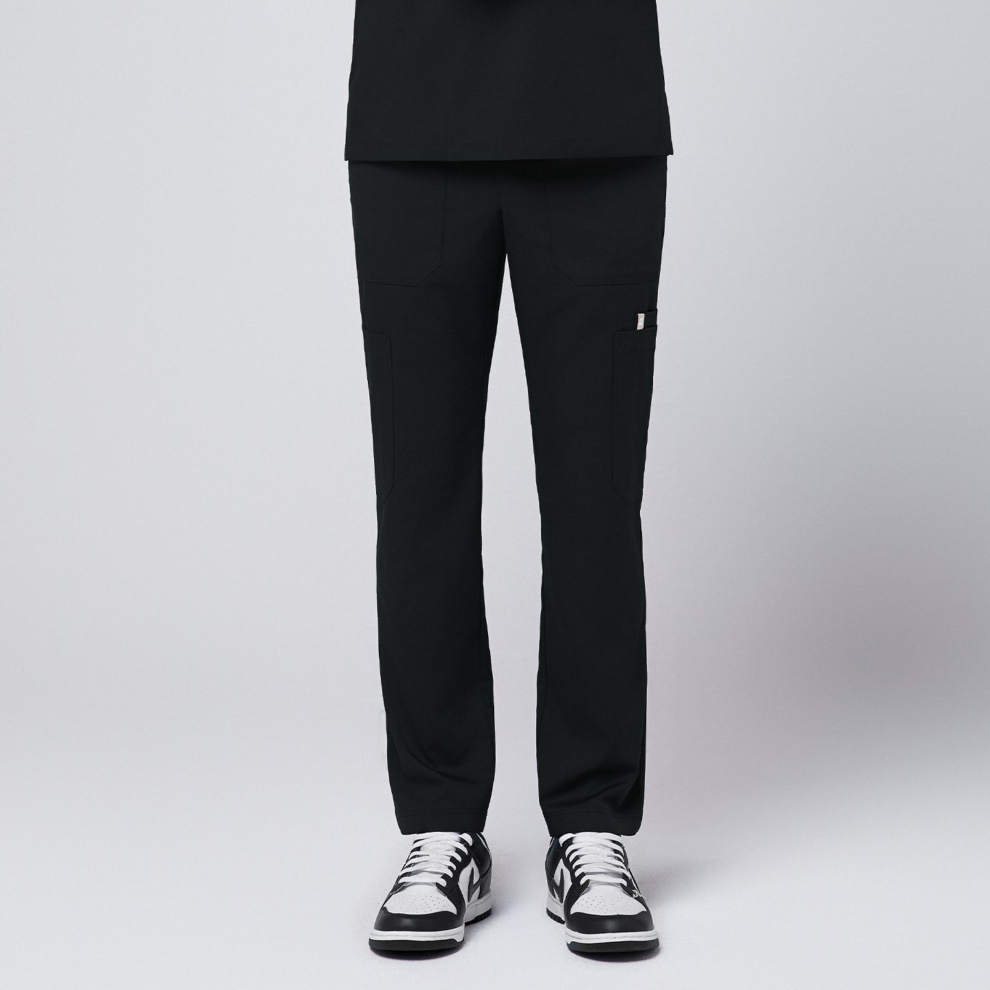 man standing, wearing Zenir eco-black 8-pocket scrub pants and black-and-white sneakers,Eco Black