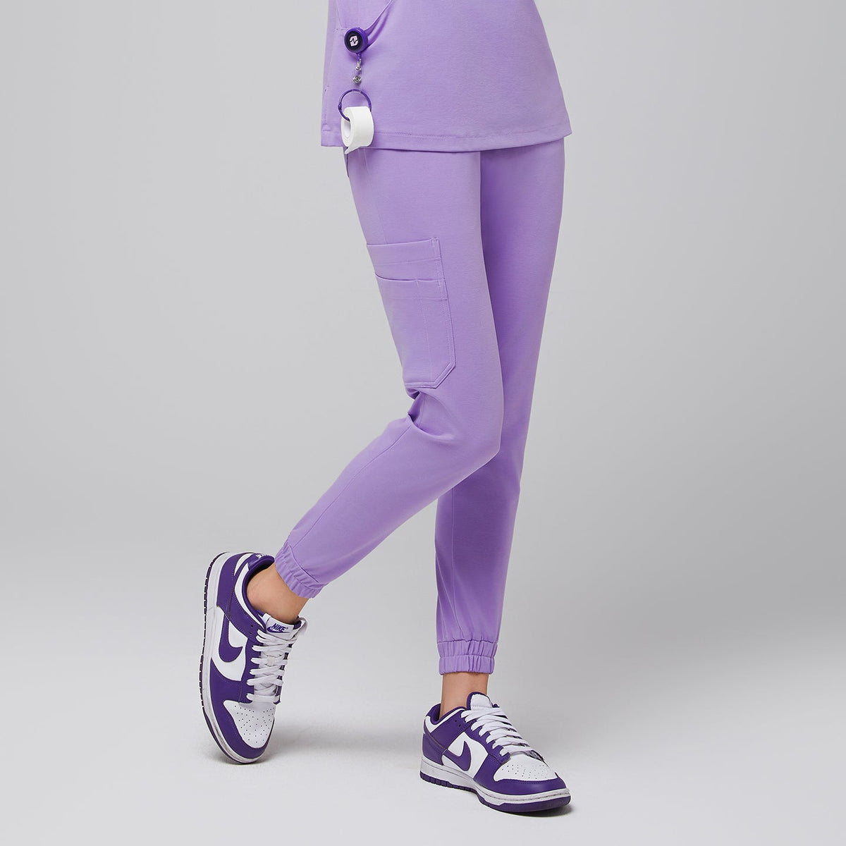 Female wearing lavender jogger scrub pants with side pockets, paired with purple and white sneakers,Lavender
