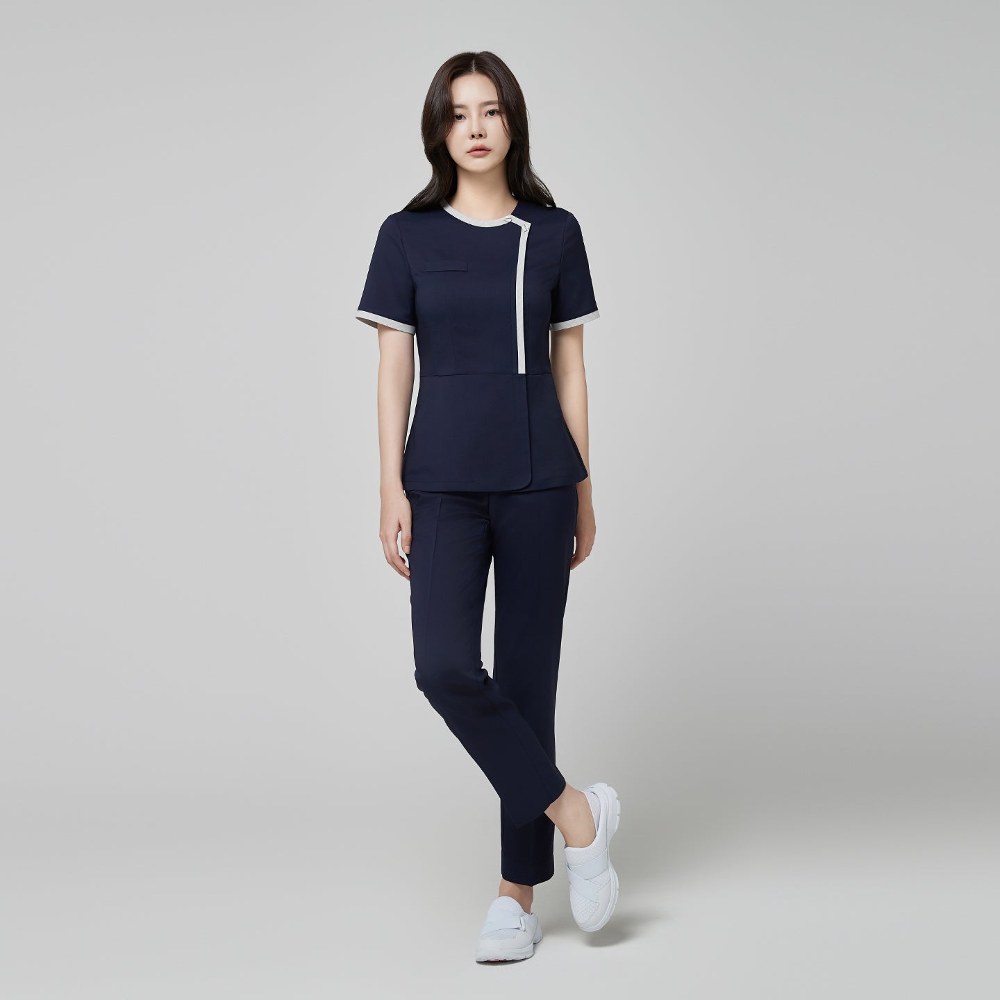 Model wearing TUL NS-174 Mir Navy scrub top with a check gray round collar, showcasing a modern, polished fit and coordinating navy pants.