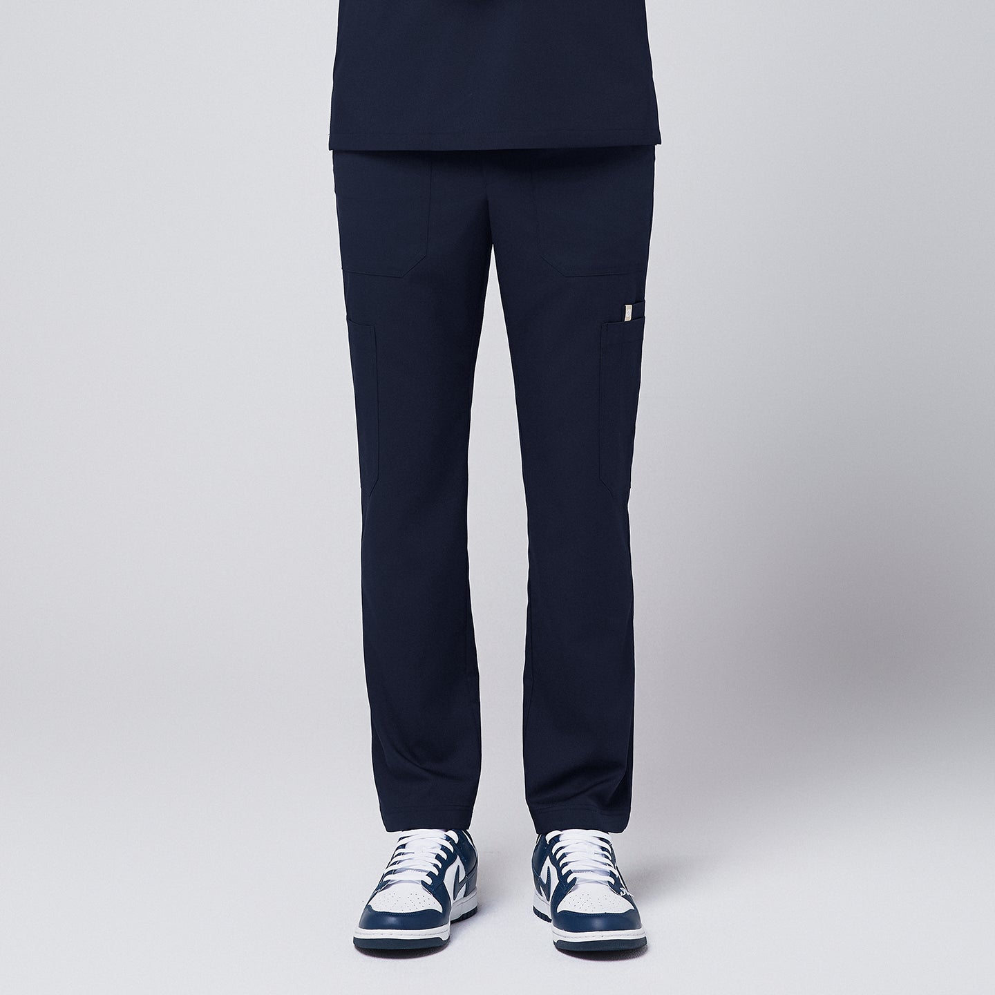 Close-up of Zenir navy 8-pocket straight scrub pants paired with blue and white sneakers,Navy