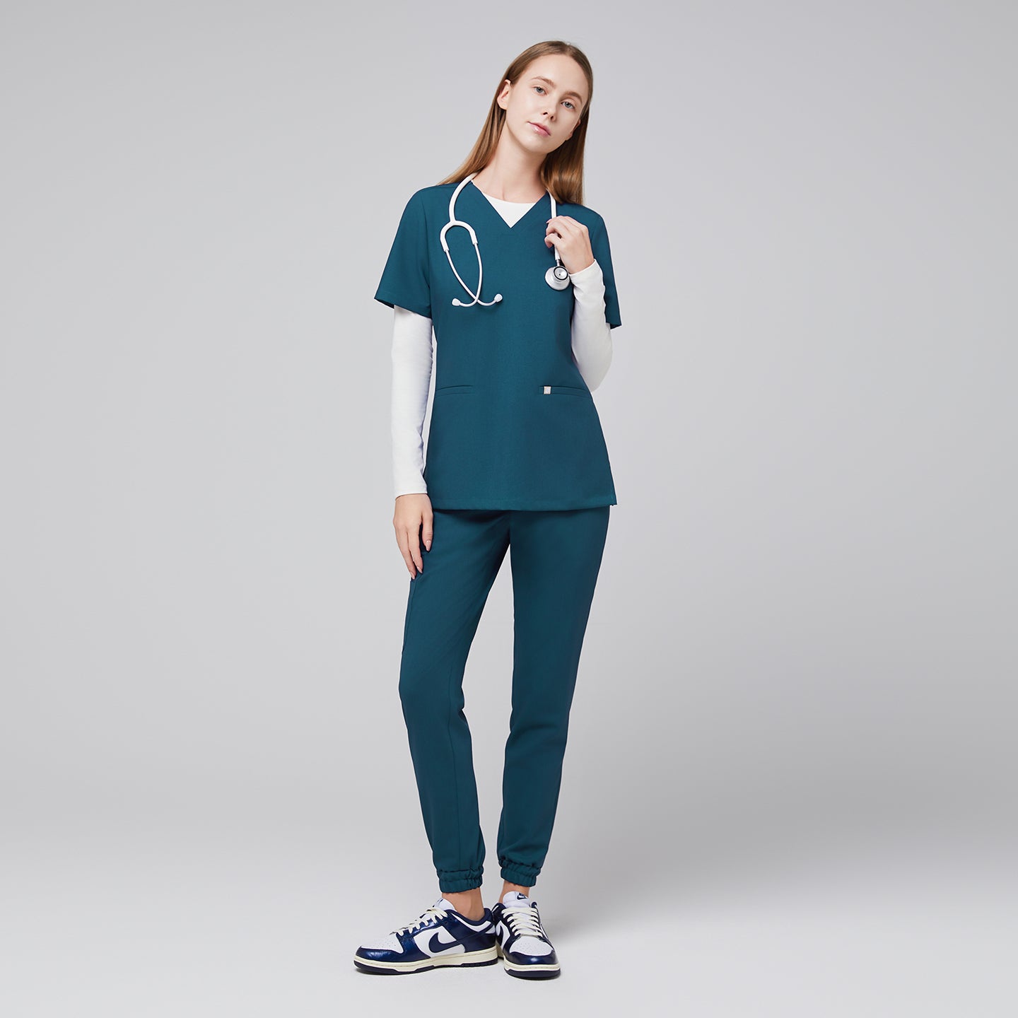 Female in teal jogger scrub pants and top with a stethoscope, paired with navy and white sneakers,Ocean Teal