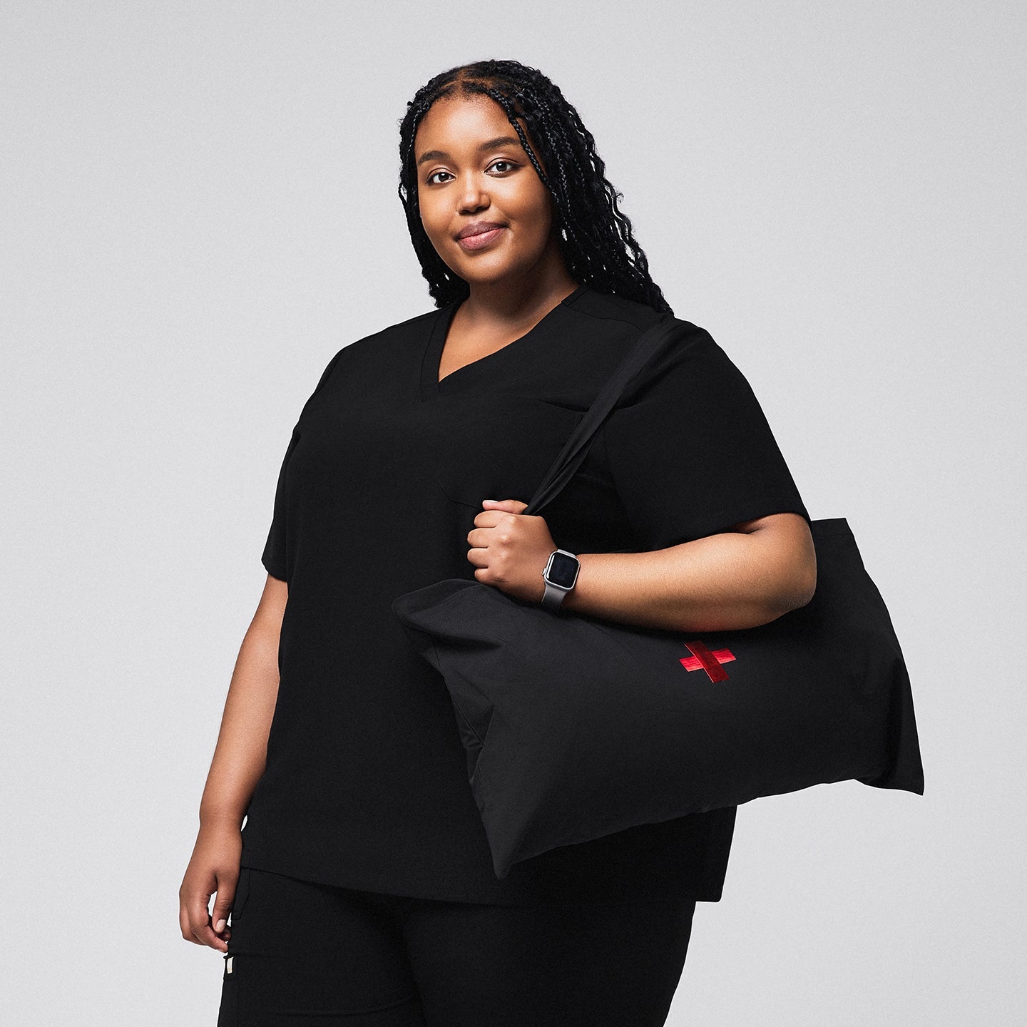 Female medical professional wearing a black scrub top, holding a large black bag with a red cross symbol, and smiling confidently,Rich Black