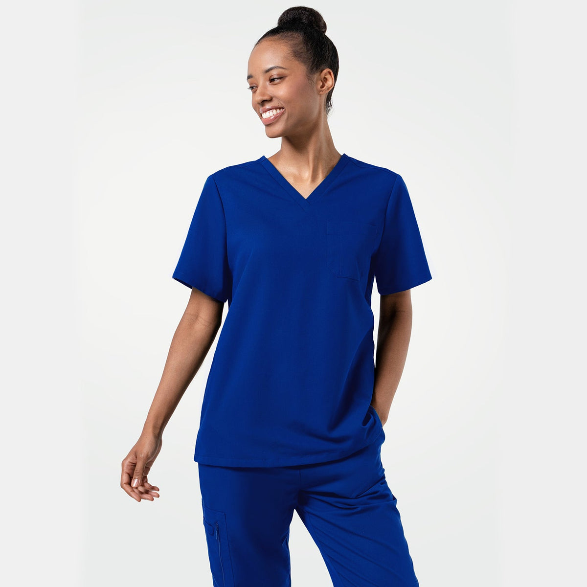 Female model smiling while wearing the Women's Royal Blue 3-Pocket Scrub Top, with one hand in the pocket