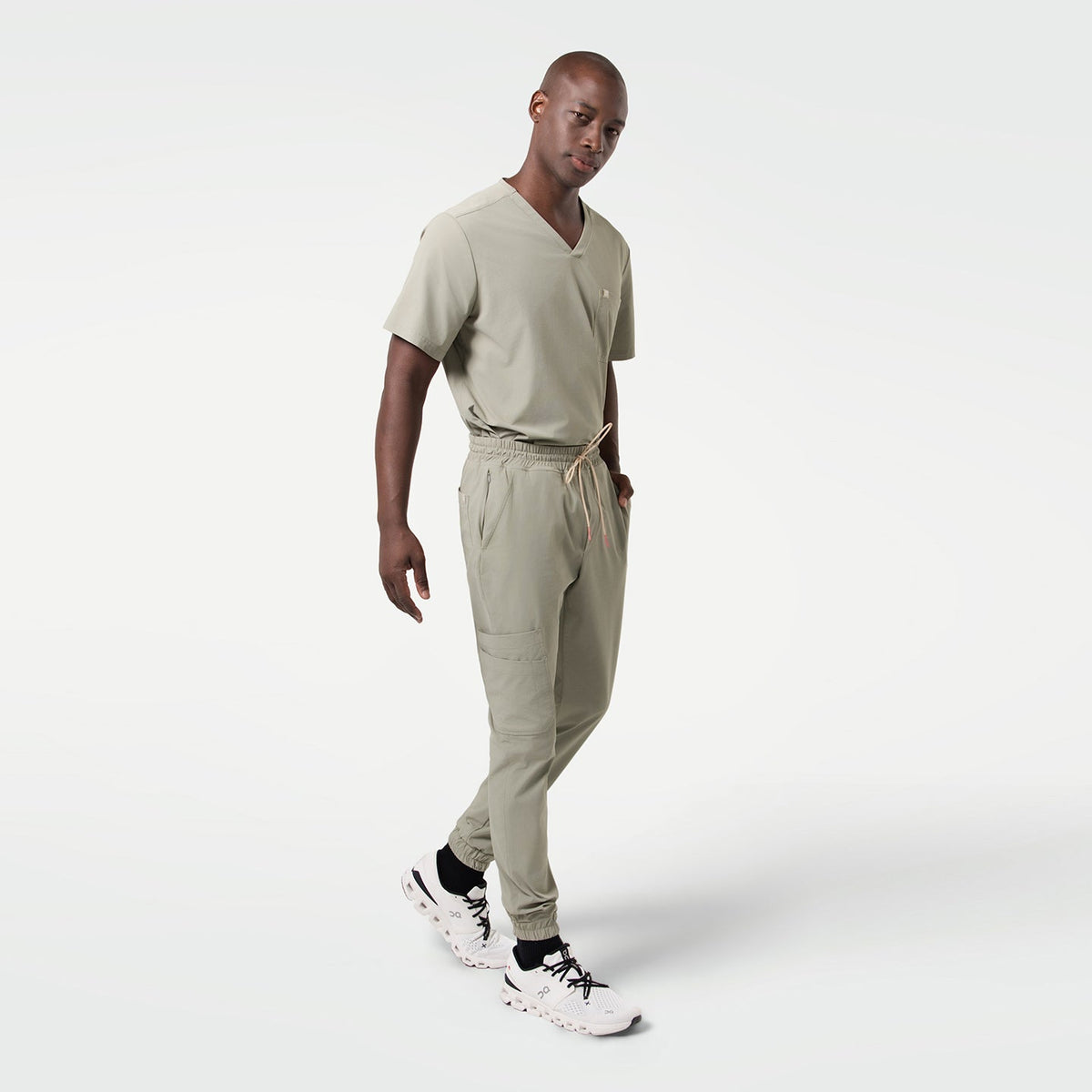 The Sand Khaki Single Pocket Scrub Top features a sleek minimalist design with a soft neutral tone.