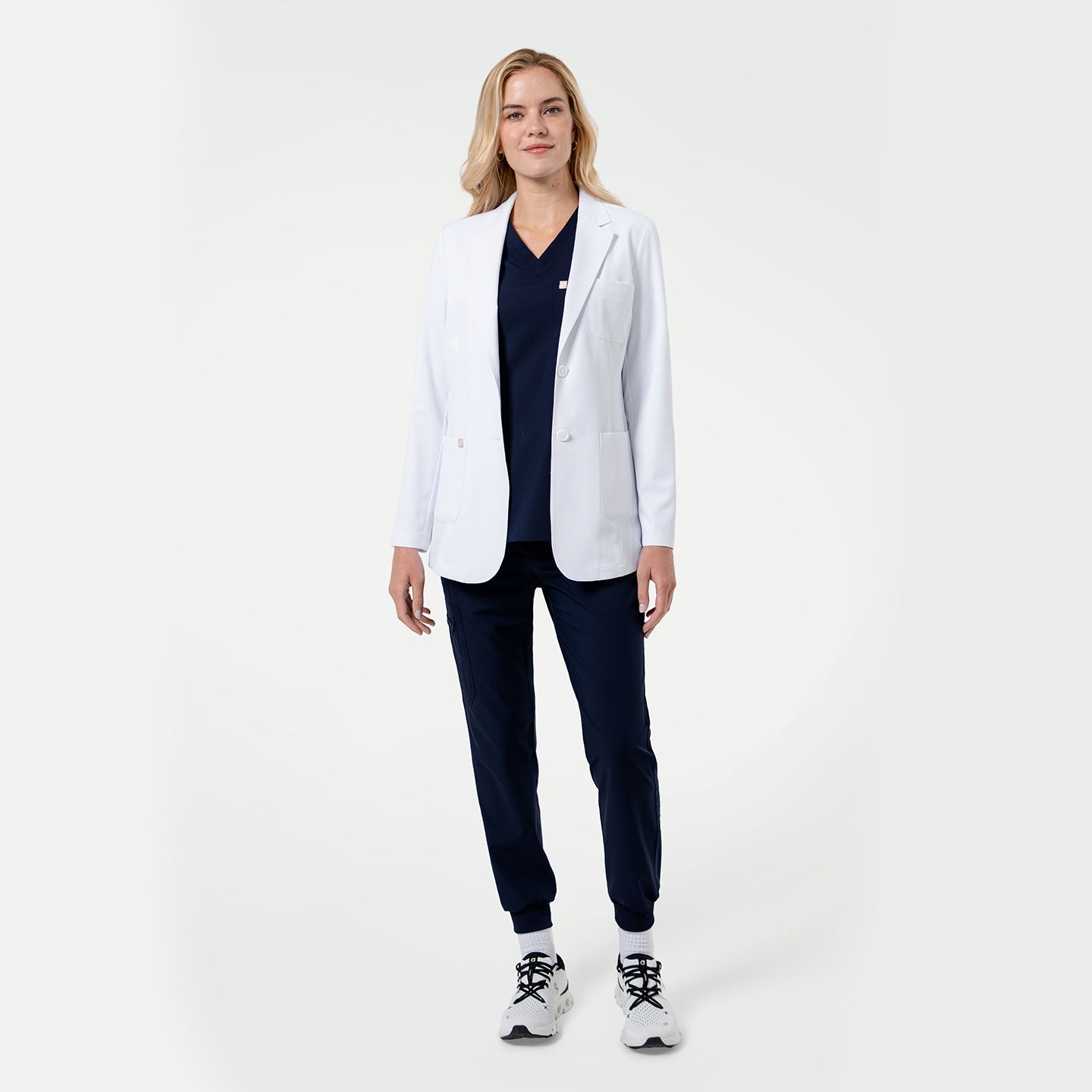 Model wearing a white medical lab coat over navy scrubs, showcasing the professional fit on a light gray background.