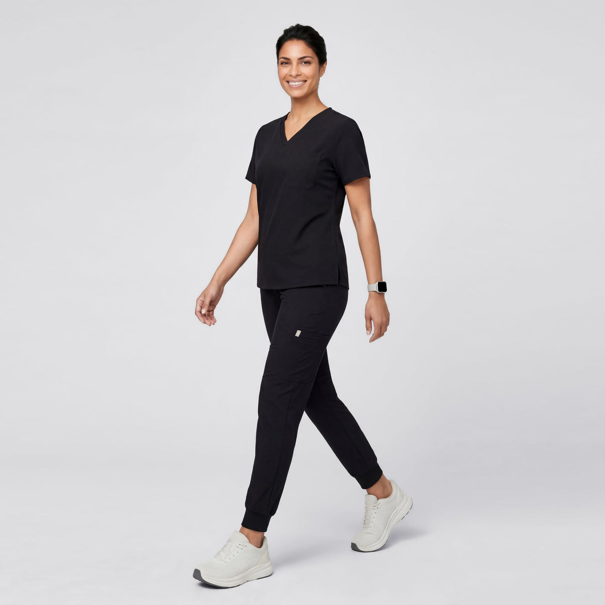 Model wearing Eco Black 3 Pocket Scrub Top, shown from the side while walking.