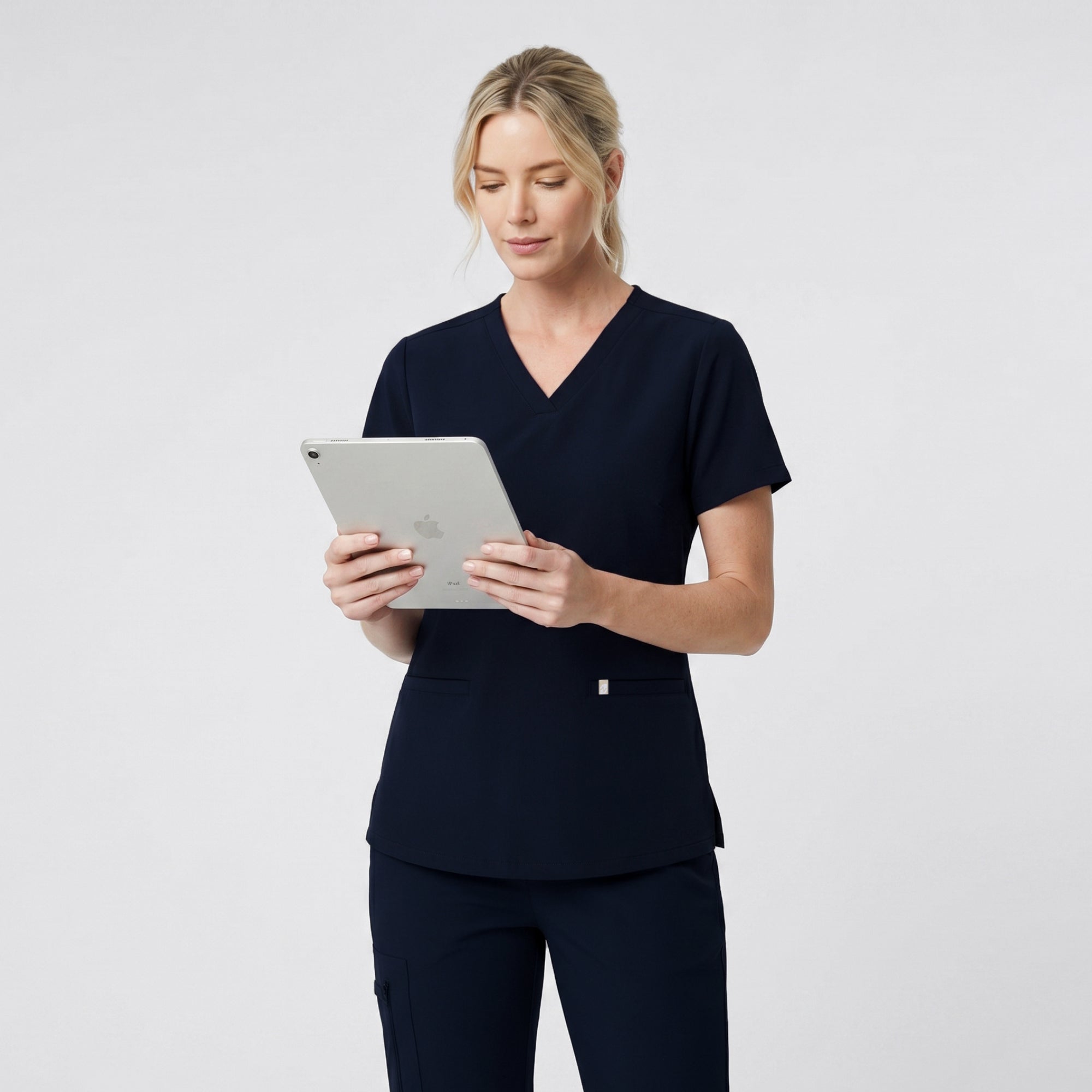 Back view of the Eco Navy Double Pocket Scrub Top worn with matching scrub pants.