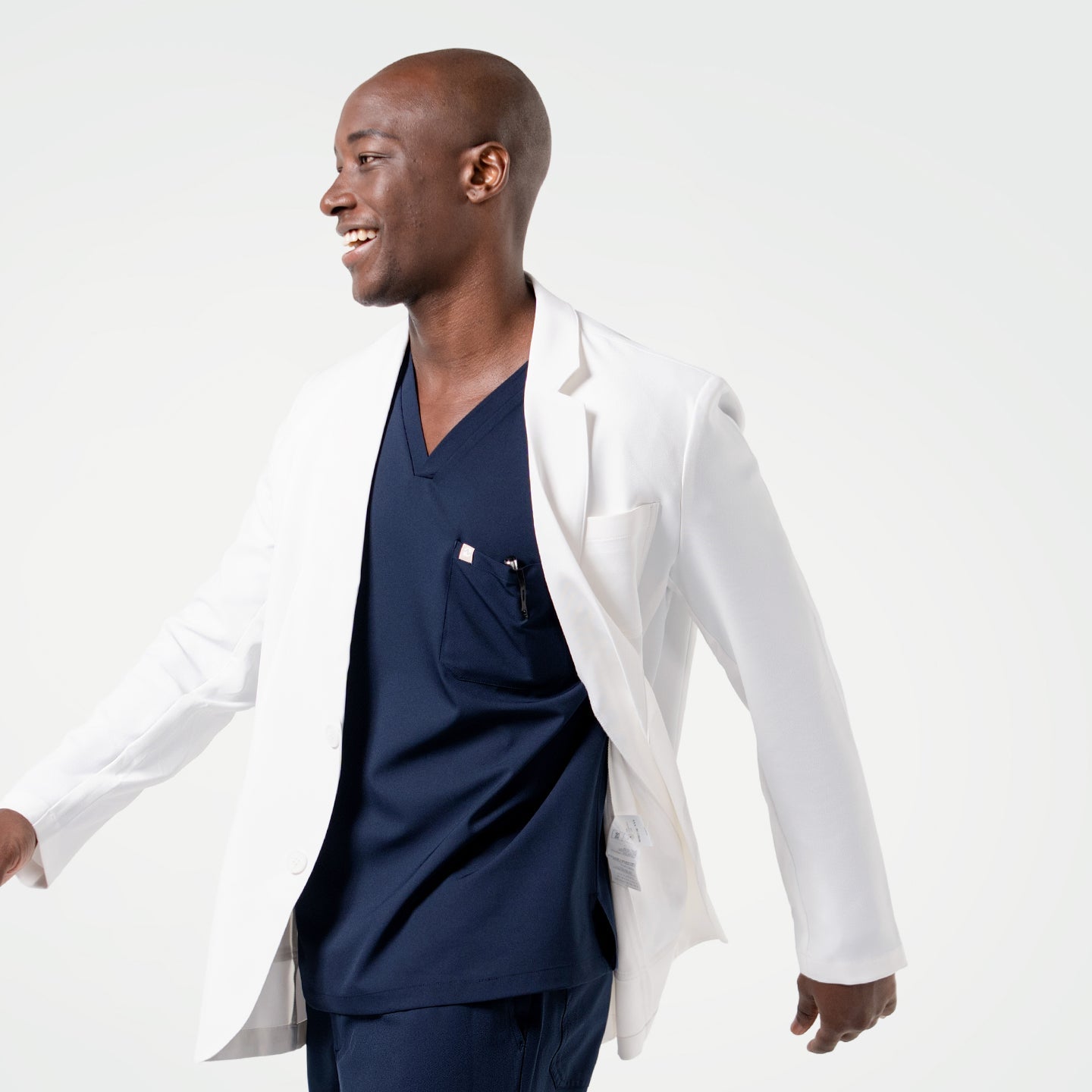 Wearing the Men’s LCM-100 Lab Coat, the model is captured in motion with a bright smile.