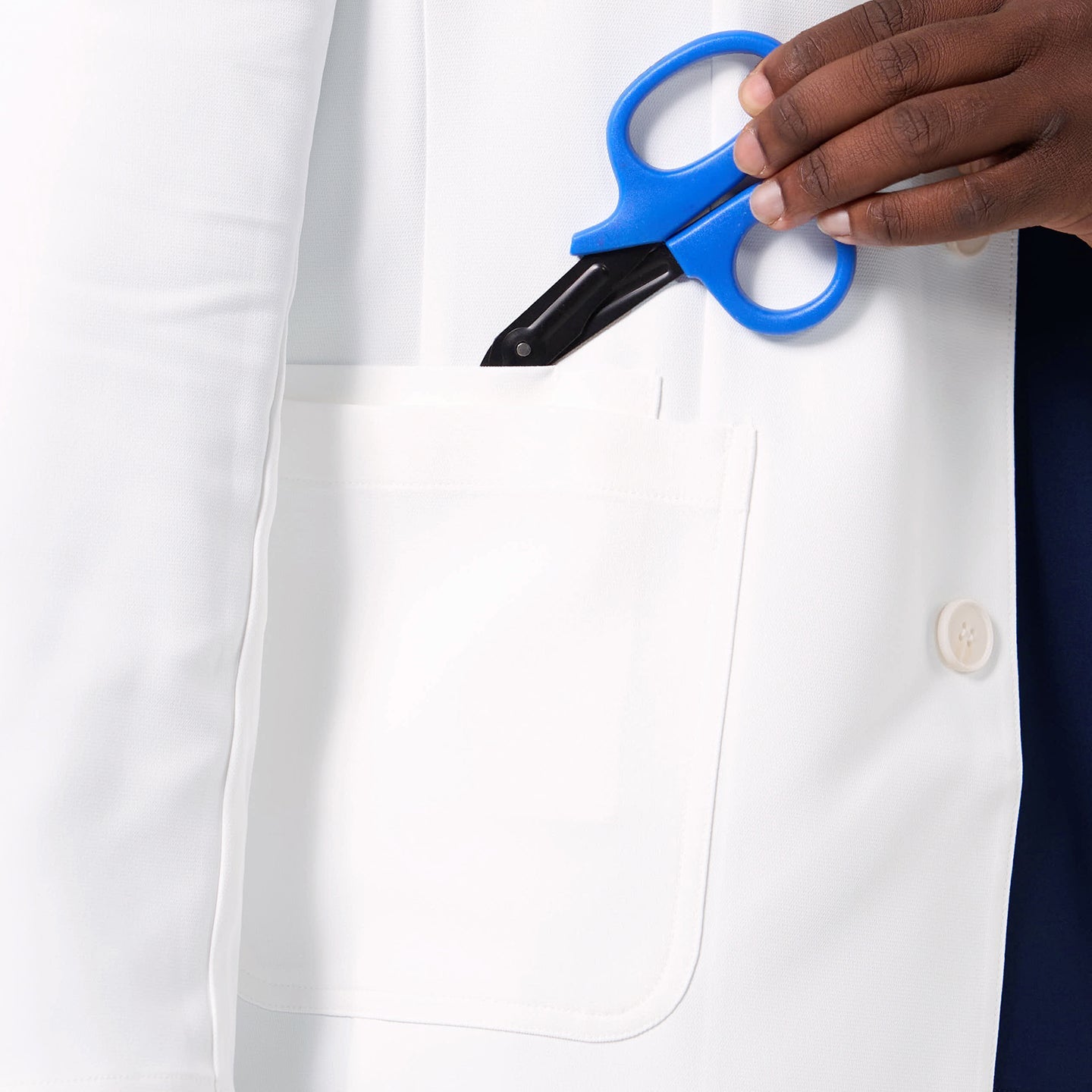 A close-up of the Men’s LCM-100 Lab Coat highlights the functional chest pocket with medical scissors placed inside.