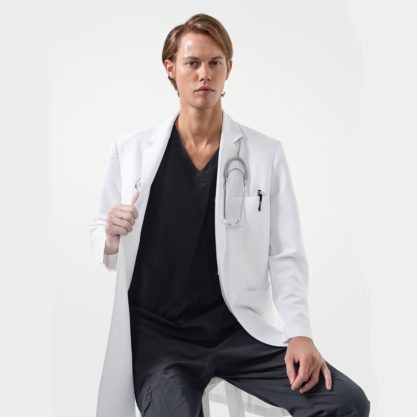 Lcm-103 men’s white lab coat with stethoscope, worn over black scrubs, professional medical uniform.
