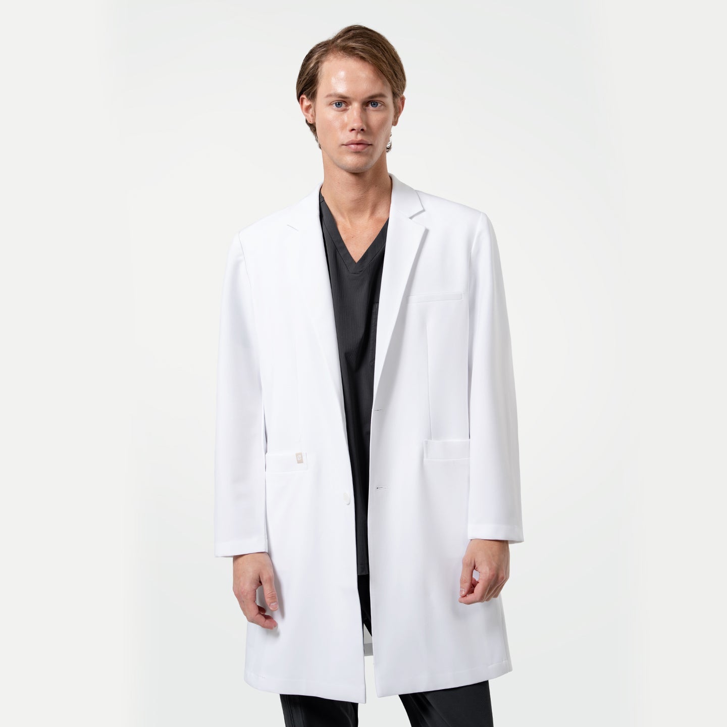 Lcm-103 men’s white lab coat front view, worn over black scrubs, featuring modern tailored fit and clean professional design.