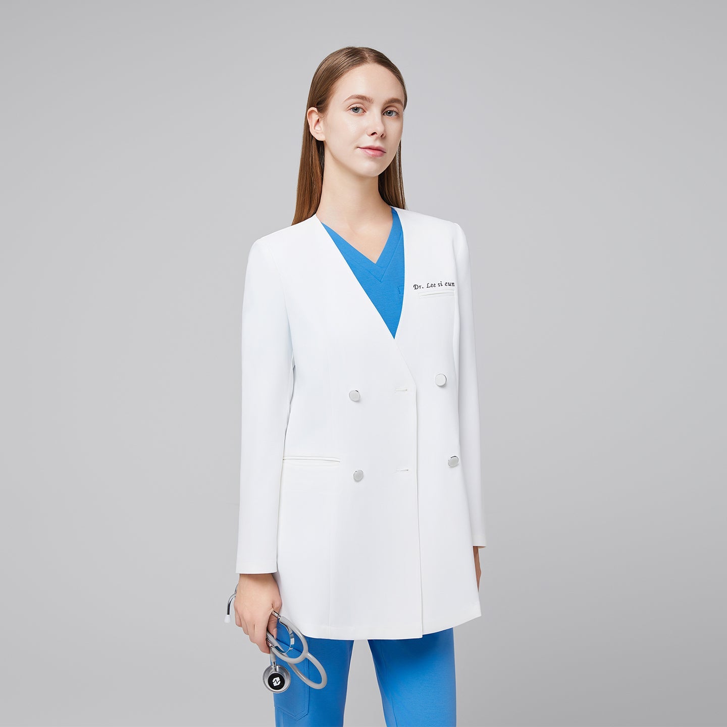 Female doctor in white double-breasted lab coat with embroidered name, wearing blue scrubs and holding a stethoscope, portraying a professional appearance,White
