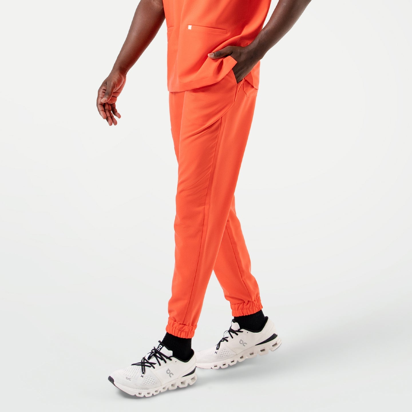 Close-up view of the StretchFit Jogger Scrub Pants in Tiger Orange as the model walks forward.