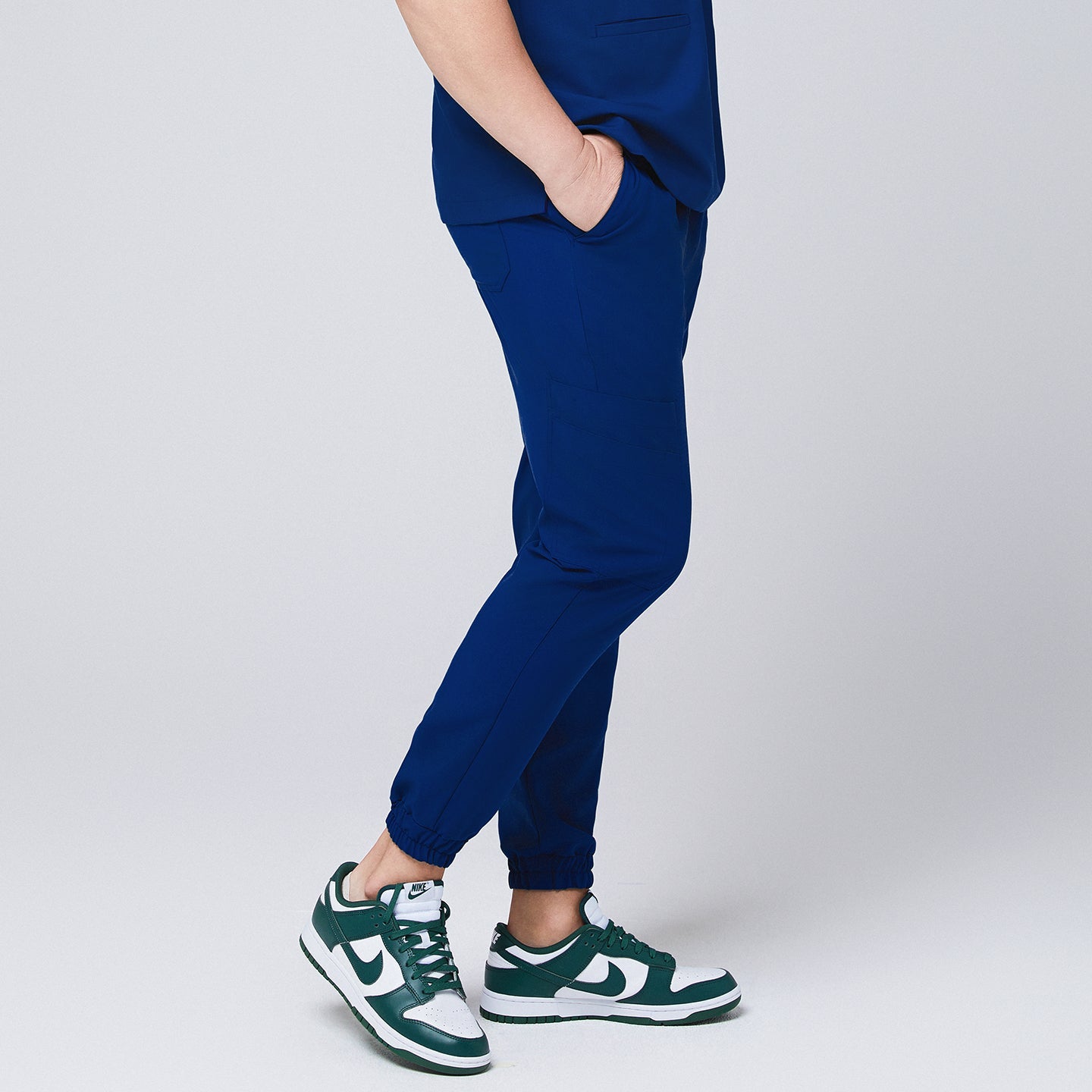 Side view of Zenir Admiral Blue jogger scrub pants with elastic cuffs and a functional pocket, paired with green sneakers for a sleek look, Admiral Blue