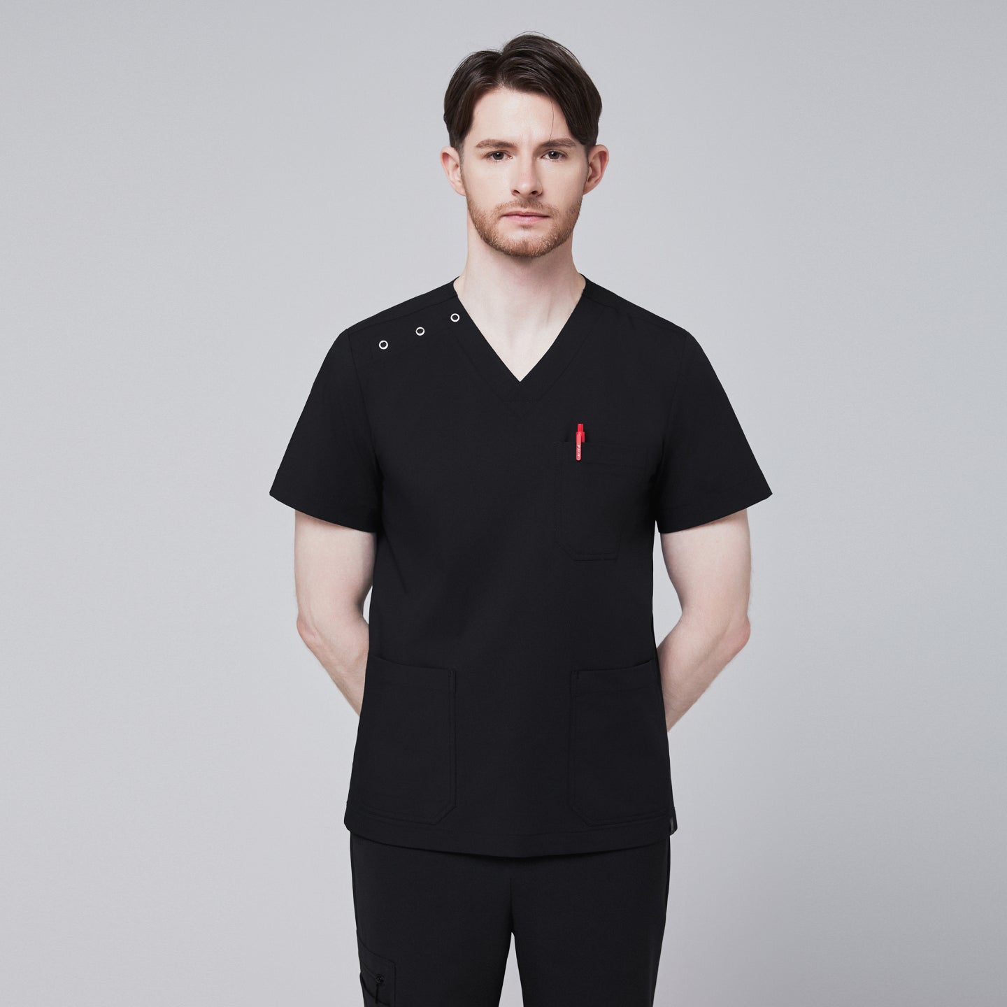 Man wearing Zenir black shoulder button scrub top with chest and lower pockets, featuring a red pen in the chest pocket,Eco Black