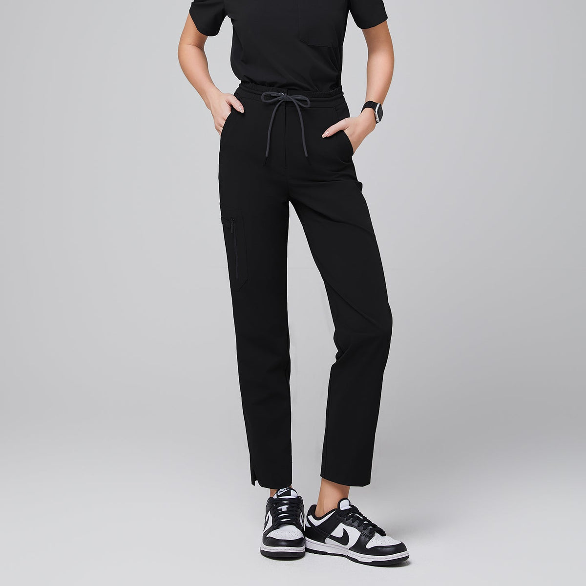 Tailored scrub pants with a drawstring waist, a functional zipper pocket on the side, and split hem details, styled with athletic sneakers for a polished and practical appearance,Eco Black