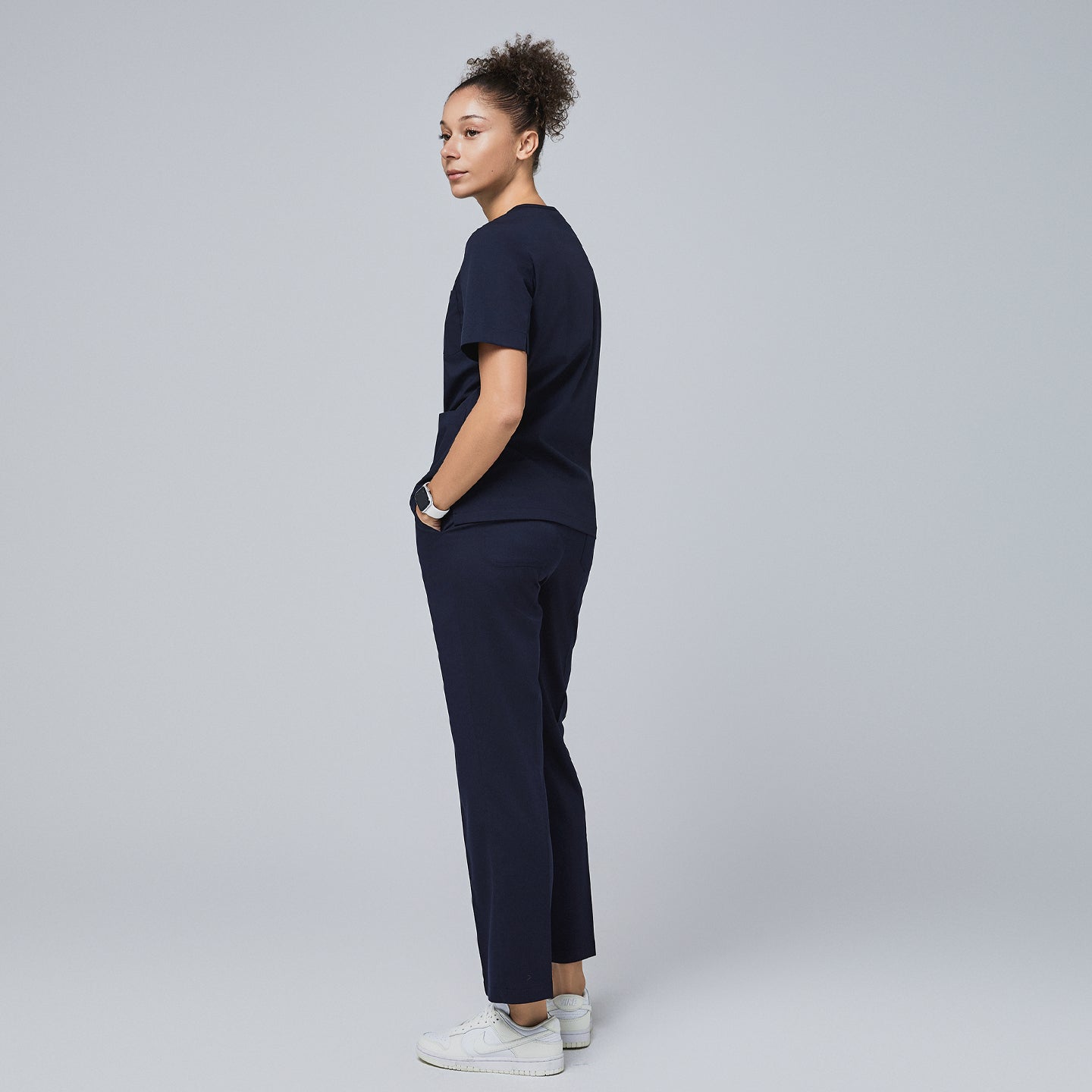 Model wearing an eco navy scrub set, standing with hands in pockets, looking over shoulder,Eco Navy