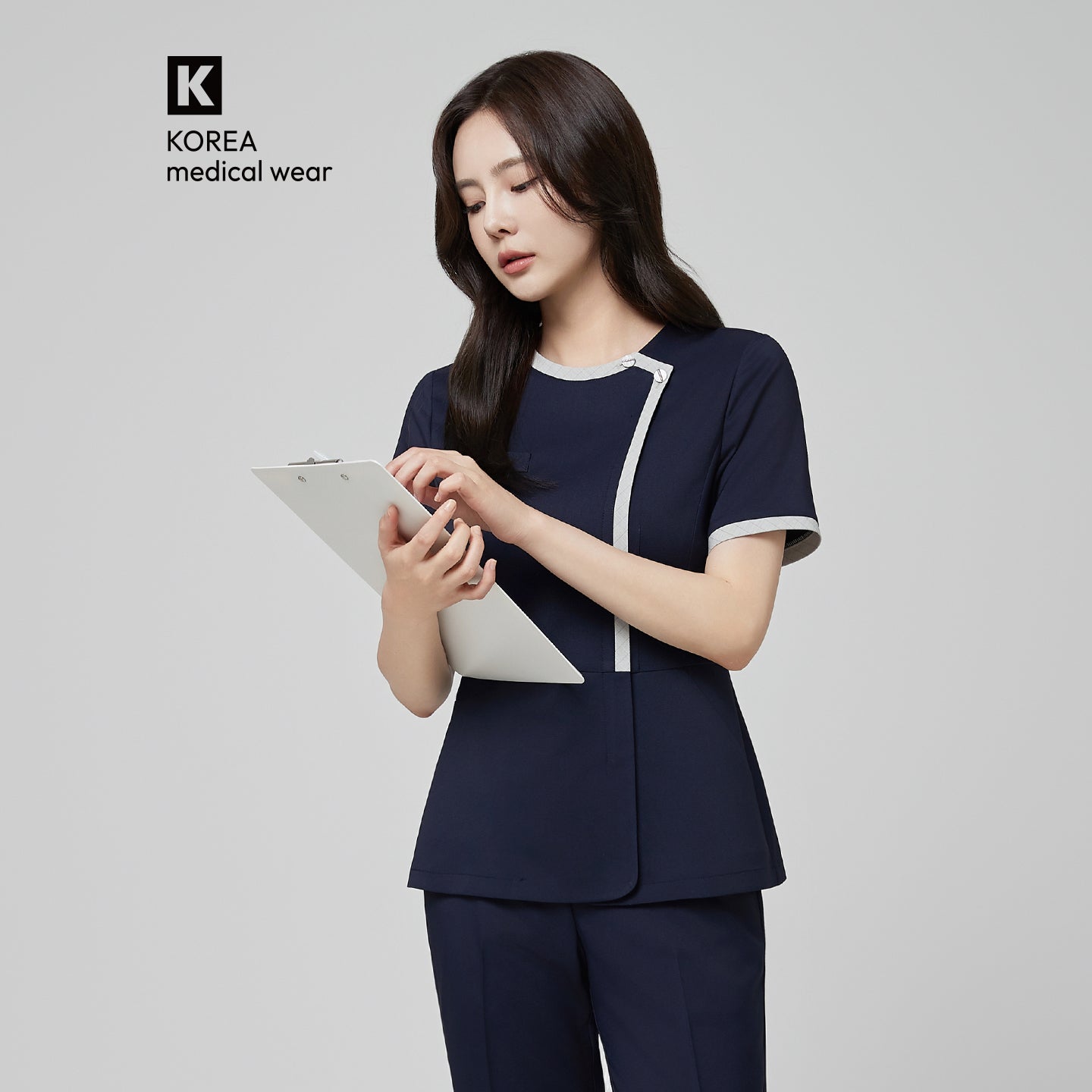 Model wearing TUL NS-174 Women’s Check Gray Round Collar Scrub Top in Mir Navy, featuring a contrasting gray trim around the neckline and front.
