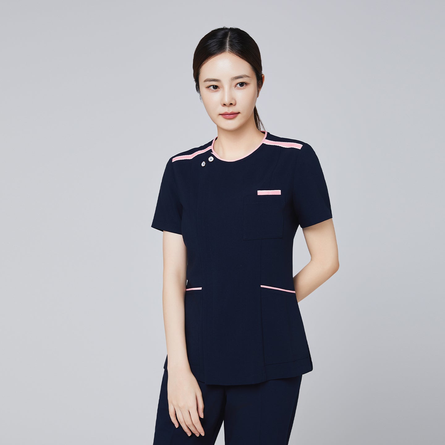 Navy scrub top with pink edge detailing and front pocket, modeled by a woman for professional settings,Navy