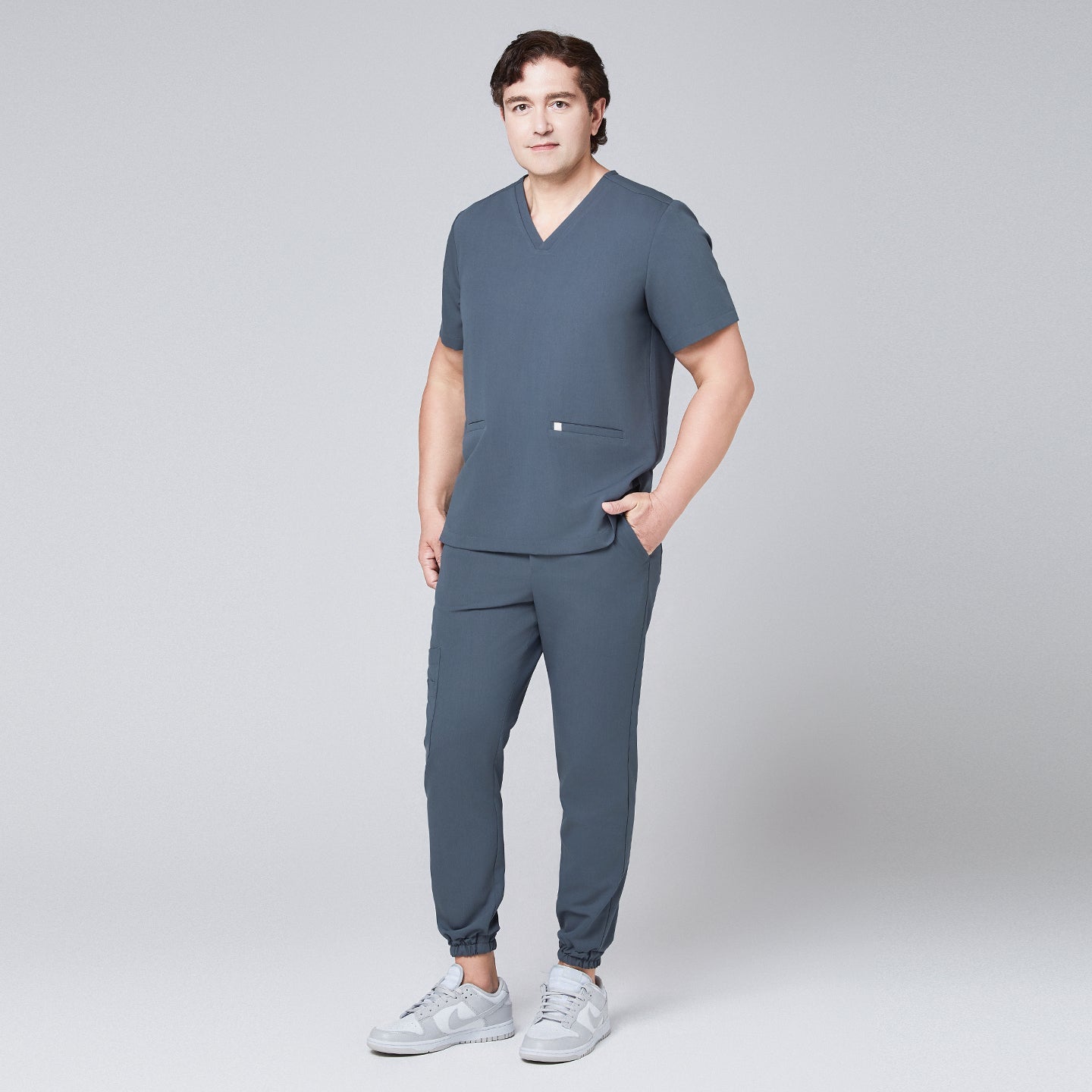 Full-body view of a man in a smoky blue scrub set with jogger pants and a double-pocket V-neck top,Smoky Blue