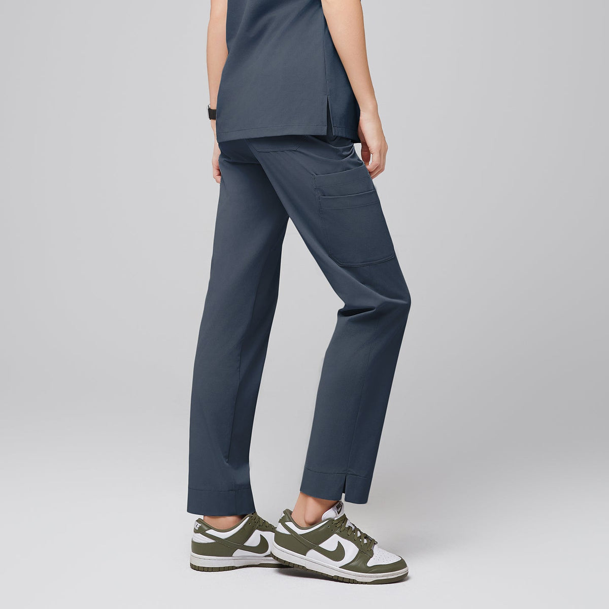 Female wearing smoky blue scrub pants with side pockets, shown from the back, paired with green and white sneakers,Smoky Blue