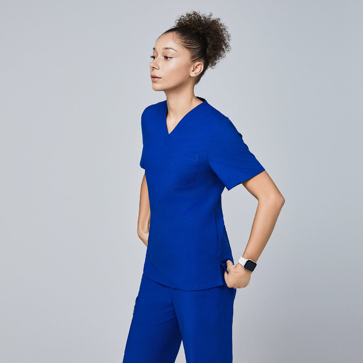 Side profile of a model wearing Zenir royal blue 3-pocket scrub top and matching pants,Royal Blue